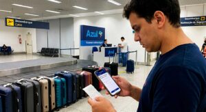 Passageiro consultando o smartphone ao lado de malas em aeroporto para post sobre rastreamento de bagagem na Azul.